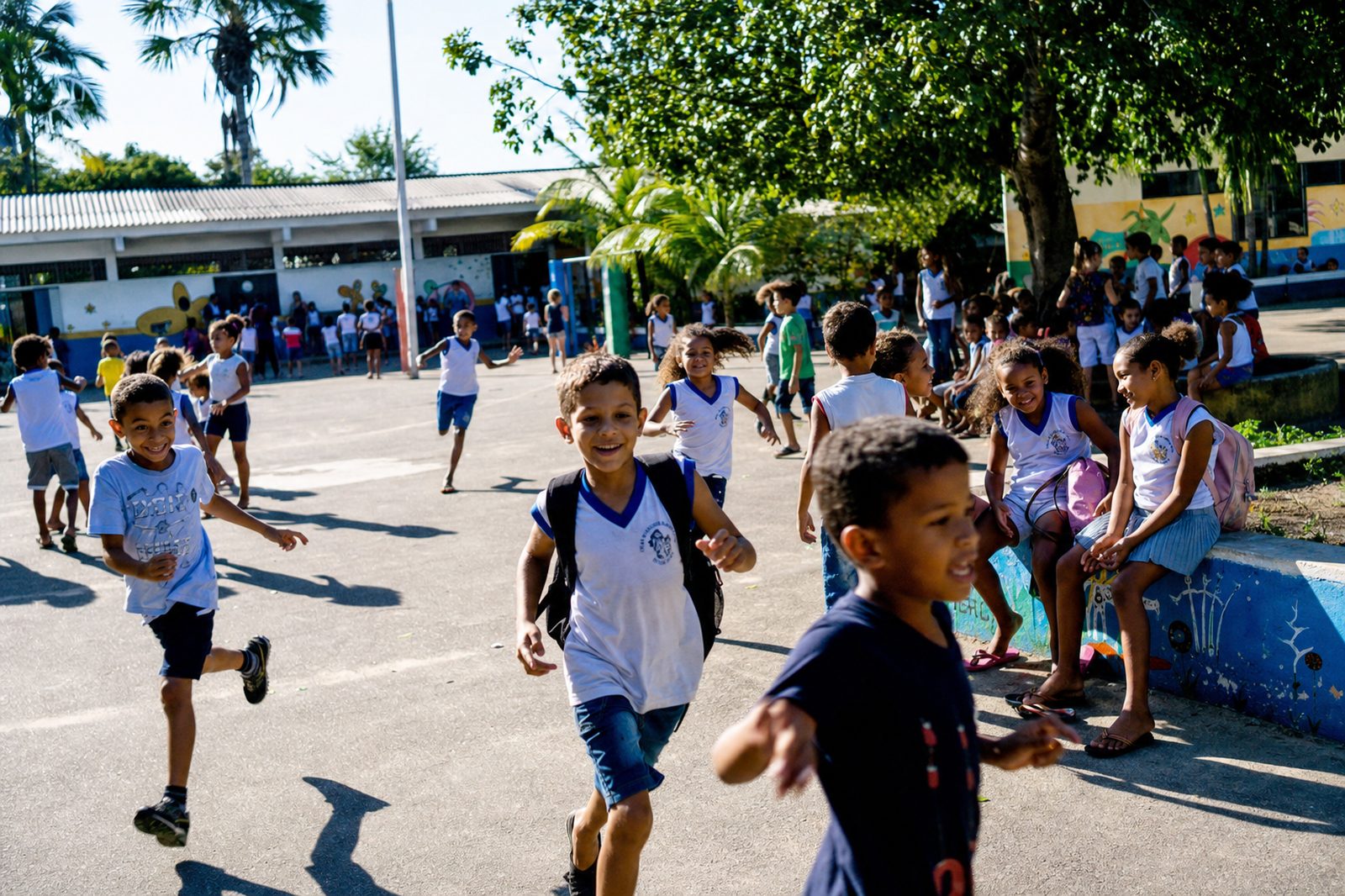 Estudantes de uniforme correndo e conversando no pátio de uma escola municipal